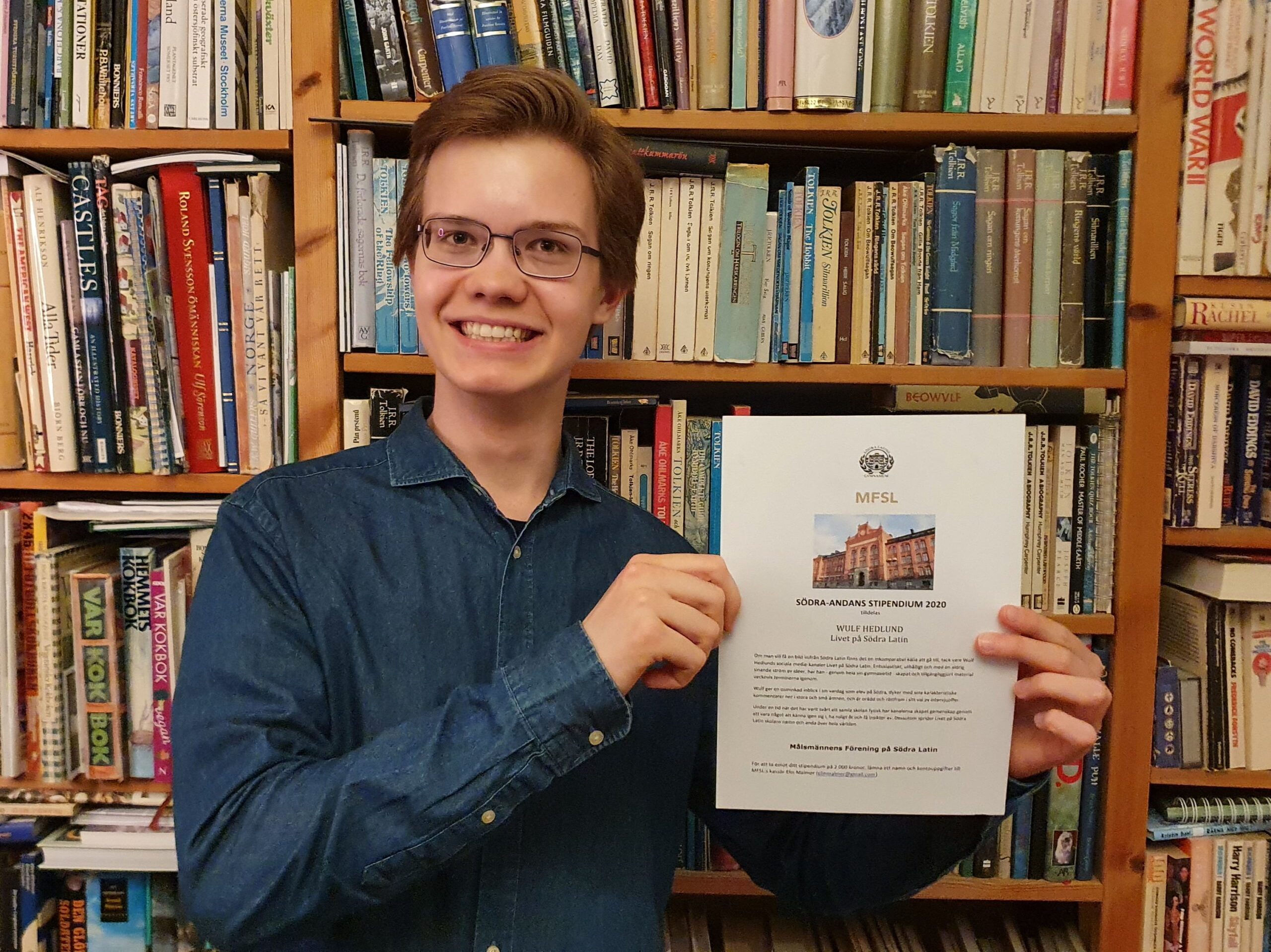 Foto på Wulf Hedlund med diplom i ett bibliotek.